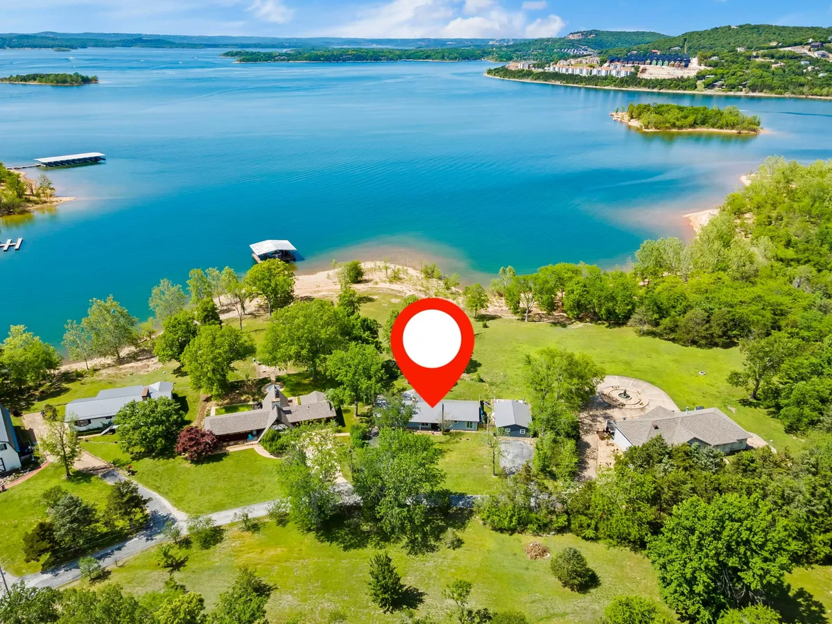 A scenic exterior shot of a tranquil lake bordered by lush greenery, with homes nestled along the shoreline. The sun casts a warm glow over the water, suggesting a peaceful sunset. Boating and fishing can be imagined on the water, while picnic areas and hiking trails blend into the natural landscape.
