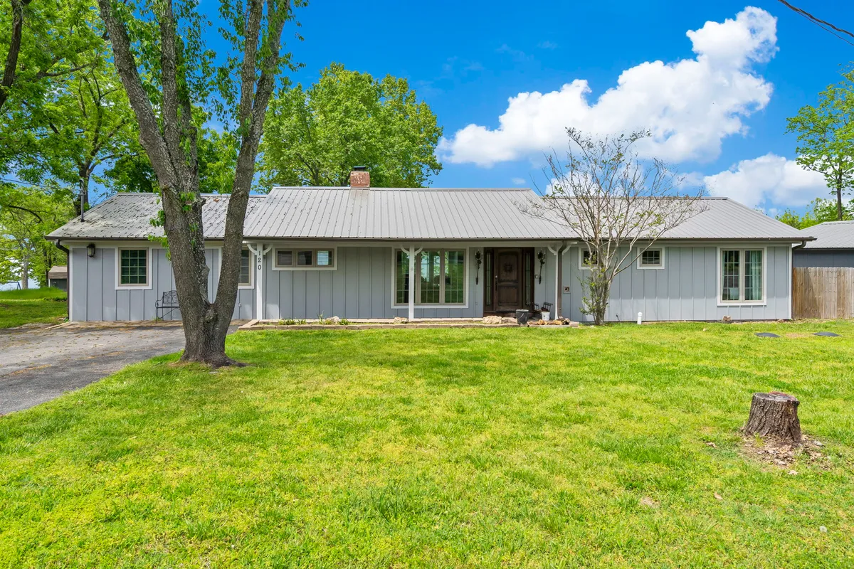 This exterior shot features the welcoming front of the home, set beneath a leafy canopy, with windows and the front door visible. The scene captures the inviting and communal atmosphere of the property.