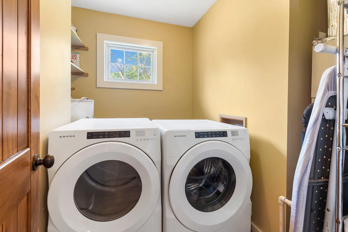 A practical laundry room with a washer, dryer, window for natural light, and organized shelves. This interior space is designed for effortless household routines, ensuring guests can manage pet messes or enjoy fresh linens during their stay.