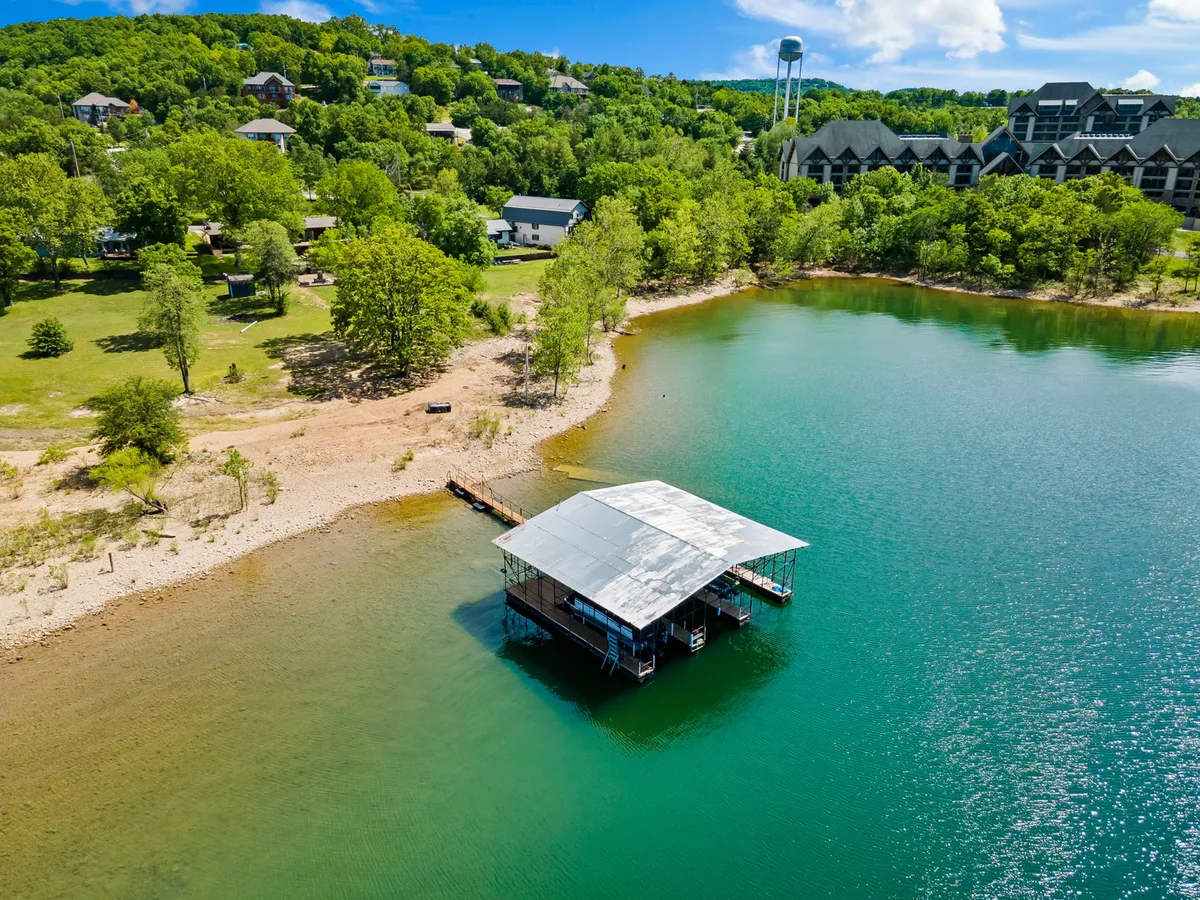 A tranquil lakeside dock scene bordered by trees and homes, with the dock extending over calm water. The setting is ideal for boating, fishing, or simply soaking in sunset views, highlighting the lakeside amenities.