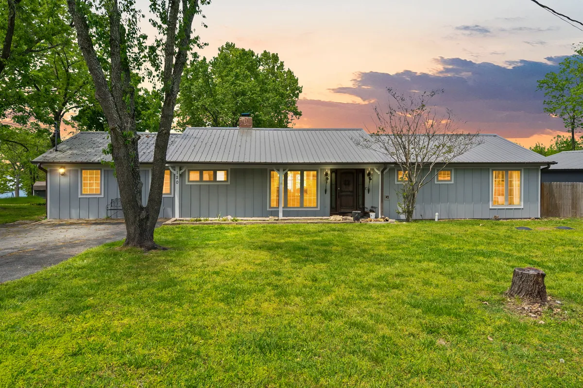 The inviting front entrance of the lodge features large windows and a spacious front yard, perfect for outdoor gatherings. The porch offers a place to relax and take in sunset views.